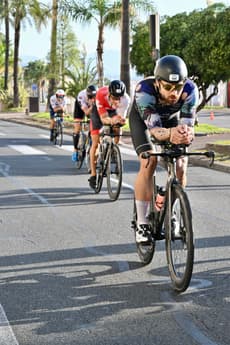 Christian Plesca on the time trial bike on a palm lined road on the bike course.