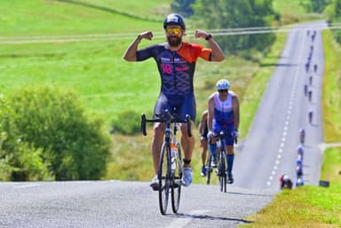 Christian Plesca flexing both arms on the road bike during a cycling event.